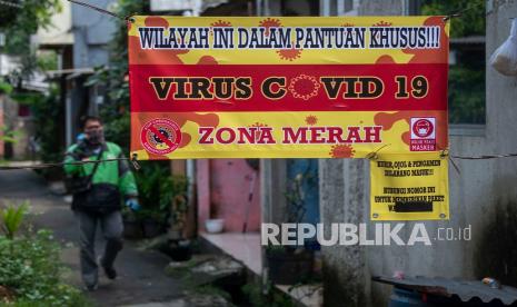 Pengemudi ojek daring berjalan di Gang Haji Usman Tepos yang diberlakukan karantina di Srengseng Sawah, Jagakarsa, Jakarta, Ahad (30/5/2021). Kampung yang dihuni sekitar 40 warga tersebut dikarantina dan dalam pantauan khusus oleh Satgas Covid-19 setempat setelah belasan warganya positif virus corona (SARS-CoV-2).