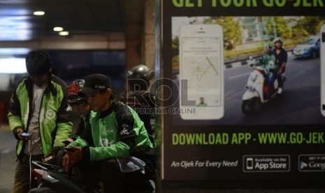  Pengemudi ojek online menunggu penumpang di Kawasan Sudirman, Jakarta Selatan, Jumat (18/12).