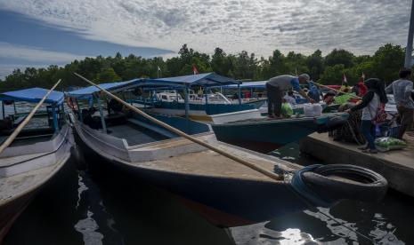 Pengemudi perahu membantu membawa barang milik penumpang yang menyeberang ke Pulau Karampuan di Pelabuhan Mamuju, Sulawesi Barat, Kamis (24/3/2022). Perahu adalah sarana transportasi utama ke pulau yang terletak di Selat Makassar tersebut dengan tarif Rp10 ribu pergi-pulang per penumpang warga pulau dan Rp20 ribu per penumpang nonwarga pulau.