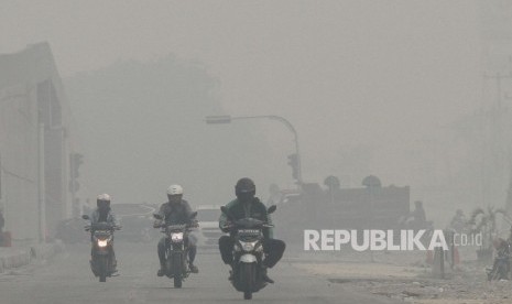 Pengendara kendaraan bermotor melintas di jalan Soekarno Hatta ketika kabut asap pekat dampak karhutla menyelimuti Kota Pekanbaru, Riau, Selasa (17/9/2019). 