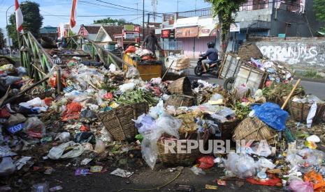 Pengendara melaju di samping tumpukan sampah di tempat penampungan sampah sementara (ilustrasi)