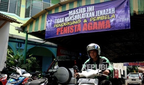 Pengendara melintas di bawah spanduk larangan mensholatkan jenazah pendukung dan pembela penista agama yang terpasang di Masjid Al-Jihad, Setiabudi, Jakarta, Ahad (26/2).