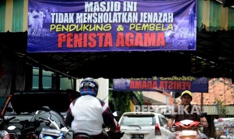 Pengendara melintas di bawah spanduk larangan menshalatkan jenazah pendukung dan pembela penista agama.