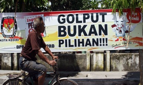 Pengendara melintas di depan atribut sosialisasi ajakan untuk tidak Golput yang dipasang di jalan raya kawasan Pesantren, Kota Kediri, Jawa Timur, Senin (7/4). 