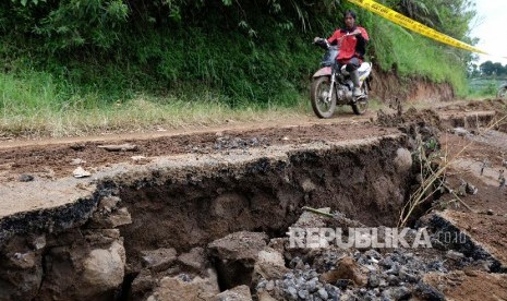 Pengendara melintas di jalan yang ambles (ilustrasi)