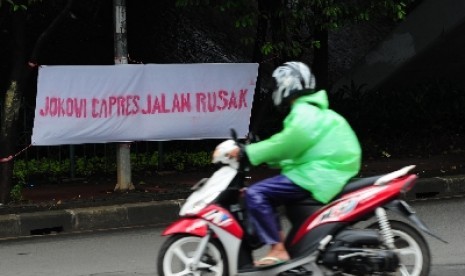 Pengendara melintas didepan spanduk kampanye hitam capres di jalan Dewi Sartika, Jakarta, Rabu (29/1). Meski belum resmi menjadi Capres, Gurbernur Joko Widodo telah mendapat serangan kampanye hitam dalam bentuk spanduk kritikan.