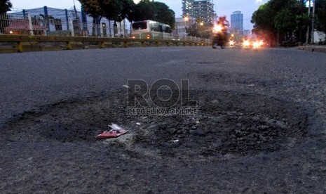 Pengendara melintasi jalan berlubang di kawasan Mampang Prapatan, Jakarta Selatan, Rabu (11/2).