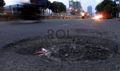 Pengendara melintasi jalan berlubang di kawasan Mampang Prapatan, Jakarta Selatan, Rabu (11/2).