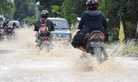 Pengendara melintasi jalan yang terendam banjir di Sendangrejo, Madiun, Jawa Timur, Selasa (5/3/2019). Luapan sejumlah anak sungai Madiun yang disebabkan hujan deras mengakibatkan beberapa wilayah di daerah itu terendam. 