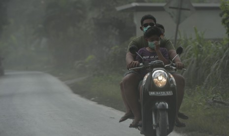 Pengendara melintasi jalan yang tertutup abu vulkanik Gunung Agung di Desa Jungutan yaitu desa yang termasuk dalam kawasan rawan bencana, Karangasem, Bali, Senin (27/11). 