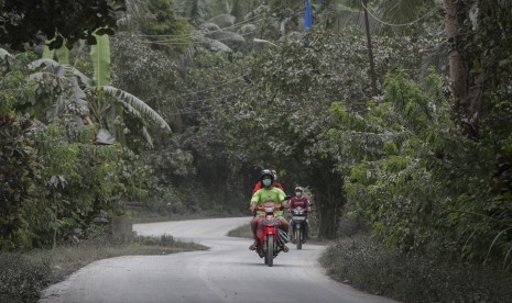 Pengendara melintasi jalan yang tertutup abu vulkanik Gunung Agung di Desa Jungutan yaitu desa yang termasuk dalam kawasan rawan bencana, Karangasem, Bali, Senin (27/11). Pusat Vulkanologi dan Mitigasi Bencana Geologi telah merekomendasikan zona awas Gunung Agung dengan radius 10 km yang meliputi 22 desa.