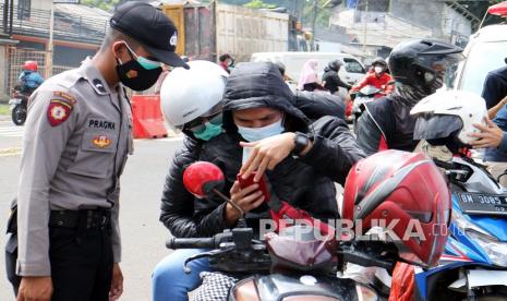 Pengendara memperlihatkan sertifikat vaksin digital kepada petugas kepolisian saat razia vaksin di jalur wisata Puncak, Kabupaten Bogor, Jawa Barat, Ahad (26/12/2021). Kepolisian menggelar razia vaksin COVID-19 kepada pengendara yang melintas menuju kawasan wisata Puncak dan memberlakukan vaksin di tempat bagi yang kedapatan belum melakukan vaksinasi. 