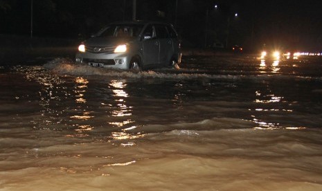 Pengendara menerobos banjir di jalan tol. 