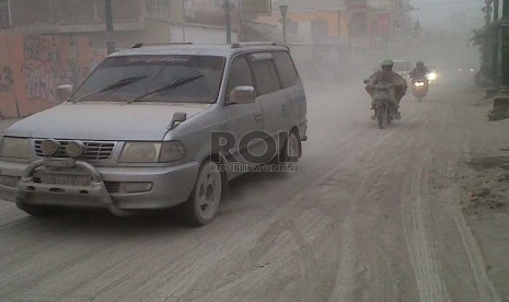 Pengendara mengenakan masker karena hujan abu