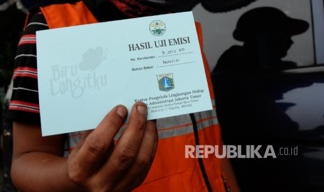 Pengendara menunjukan kartu hasil uji emisi usai melakukan uji emisi gas buang pada kendaraan roda empat yang melintas di Jalan Pemuda, Jakarta Timur, Selasa (26/4). (Republika / Yasin Habibi)