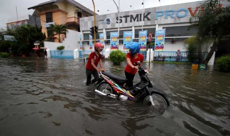 Pengendara menuntun sepeda motornya melintasi banjir di Jl. Patimura, Semarang, Jawa Tengah, Kamis (23/1). 