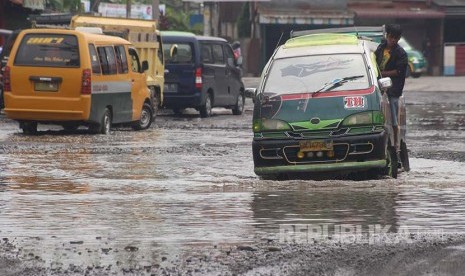 Pengendara mobil berusaha menghindari jalan rusak yang terendam air di kawasan Jalan Titi Papan Medan, Sumatera Utara, Jumat (14/10). Kerusakan jalan yang tidak kunjung diperbaiki itu kerap menimbulkan kecelakaan dan mengganggu aktivitas masyarakat. 