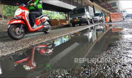 Pengendara mobil dan sepeda motor bermanuver menghindari badan jalan rusak di Jl HR Rasuna Said Jakarta, Rabu (4/1/2023). Selama proses pembangunan infrastruktur LRT jalan ini kerap rusak. 