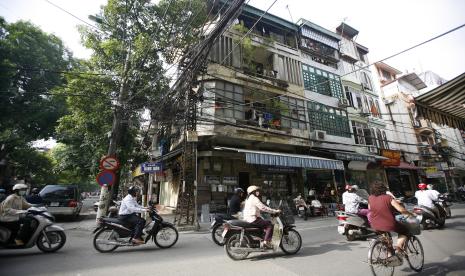 Pengendara mobil dan sepeda motor melewati kabel listrik di jalan di Hanoi. Ekonomi Vietnam melejit melampaui Indonesia.