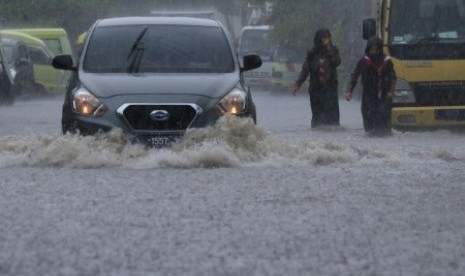 Pengendara mobil menerjang air yang menggenangi Jalan Krembangan Makam, Surabaya, Jawa Timur, Jumat (24/11). Hujan deras menyebabkan beberapa area di Surabaya tergenang air. 