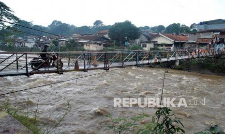 Pengendara motor melaju di atas jembatan sungai Ciliwung yang arus airnya deras, di Kelurahan Sempur, Kota Bogor, Jawa Barat, Selasa (9/2/2021). BMKG merilis anomali iklim La Nina sedang berkembang di Samudera Pasifik, dampaknya pada Indonesia dapat menyebabkan cuaca ekstrem dengan curah hujan yang tinggi serta berakibat pada bencana hidrometerologi seperti banjir dan tanah longsor. 