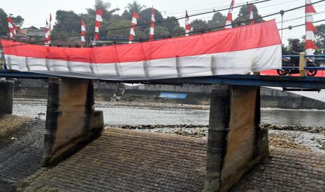 Pengendara motor melintas di atas jembatan yang telah dihias umbul-umbul dan bendera Merah Putih di Bendung Katulampa, Kota Bogor, Jawa Barat, Selasa (9/8/2022). Pemasangan umbul-umbul dan bendera Merah Putih sepanjang 25 meter tersebut dalam rangka menyambut HUT ke-77 Kemerdekaan Republik Indonesia. 