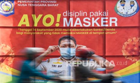 Pengendara motor melintas di dekat baliho sosialisasi AYO! Disiplin Pakai Masker? yang terpasang di depan Kantor BKD Provinsi NTB di Mataram, NTB. Satuan Tugas Penanganan COVID-19 Provinsi Nusa Tenggara Barat menyebutkan angka pasien positif baru COVID-19 di daerah itu bertambah 100 orang dalam sehari.