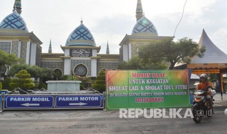 Pengendara motor melintas di dekat papan pengumuman di halaman Masjid Agung Baitul Hakim Kota Madiun, Jawa Timur, Jumat (15/5/2020). Pengurus masjid terbesar di Kota Madiun tersebut tidak menggelar shalat Lail dan Shalat Idul Fitri guna mendukung upaya pencegahan penyebaran COVID-19. 