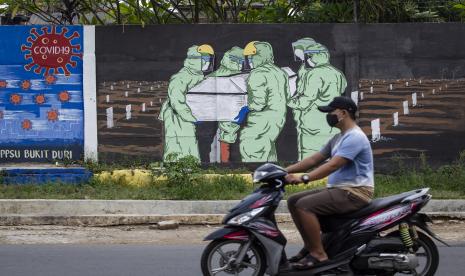 Pengendara motor melintas di depan mural tentang pandemi Covid-19. Masyarakat diminta tidak terpengaruh kabar hoaks atau misinformasi Covid-19, salah satunya dari Aliansi Dokter Dunia.