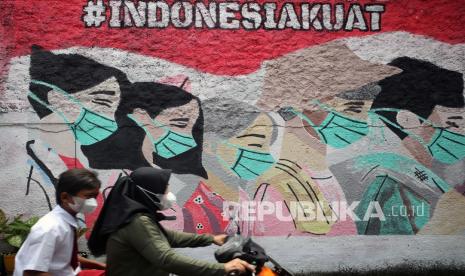 Pengendara motor melintas di depan mural yang bergambar ajakan terus tetap menggunakan masker yang ada di kawasan Cireunde, Tangerang Selatan, Banten, Selasa (15/2/2022). Tingginya angka penyebaran dan penularan COVID-19 di Tangsel membuat sejumlah warga mengajak warga yang lain tetap patuh terus menggunakan masker di tengah mulai memudarnya ketaatan penggunaan masker demi meminimalisir penyebaran COVID-19.