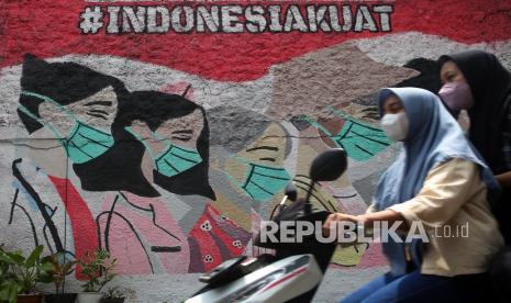 Pengendara motor melintas di depan mural yang bergambar ajakan menggunakan masker yang ada di kawasan Cireunde, Tangerang Selatan, Banten, Selasa (15/2/2022). Dinas Kesehatan Kota Tangerang Selatan (Tangsel) menyebut tingginya angka kasus Covid-19 sangat berkaitan erat dengan protokol kesehatan (prokes) yang tidak dijalankan dengan disiplin oleh masyarakat. 