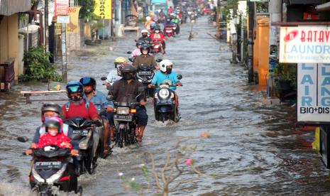 Pengendara motor melintas di jalan yang tergenang banjir di Desa Kureksari, Waru, Sidoarjo, Jawa Timur, Jumat (11/3/2022). Curah hujan tinggi dan daya tampung sungai yang belum maksimal serta drainase yang buruk mengakibatkan banjir menggenangi ruas jalan dan permukiman warga di sejumlah lokasi di Sidoarjo