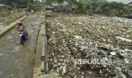 Pengendara motor melintas di samping tumpukan sampah (ilustrasi)