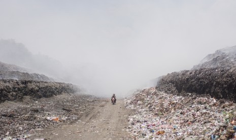 Pengendara motor melintas di Tempat Pembuangan Akhir (TPA) Sampah Putri Cempo, Mojosongo, Solo, Jawa Tengah.