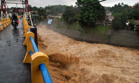 Pengendara motor melintas diatas jembatan saat tinggi muka air sungai Ciliwung naik di Bendung Katulampa, Kota Bogor, Jawa Barat.