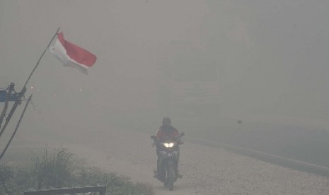 Pengendara motor melintas menembus kabut asap di kawasan Rimbo Panjang, Tambang, Kampar, Riau, Selasa (1/9).