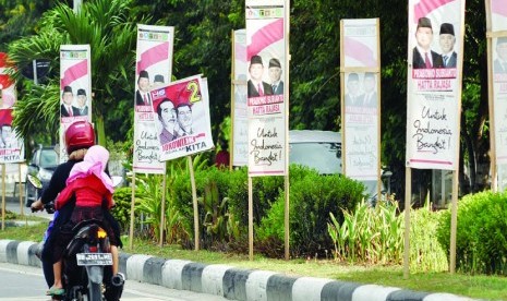 Pengendara motor melintasi deretan alat peraga kampanye pasangan capres-cawapres yang terpasang di Jalan Moh Yamin ,Palu, Sulawesi Tengah, Ahad (6/7).