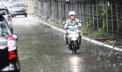 Pengendara motor melintasi hujan.