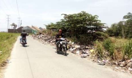 Pengendara motor melintasi jalan di tepi Sungai Cisangkuy, Jalan Rancatungku, Pameungpeuk  yang tepiannya dipenuhi sampah, Selasa (25/9). 