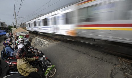 Pengendara motor menunggu KRL lewat di perlintasan kereta api tanpa palang pintu, kawasan Tambora, Jakarta Barat, Jumat (15/4). (Antara/Sigid Kurniawan)