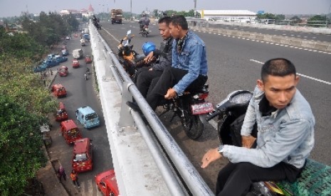 Pengendara motor tengah bersantai di sebuah flyover di Jakarta. 