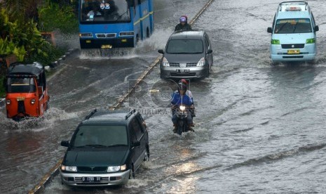 Pengendara nekad menerobos genangan air di Jalan Gunung Sahari, Jakarta, Ahad (12/1).  (Republika/Agung Supriyanto)