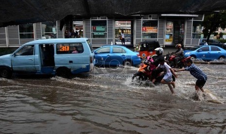 Pengendara nekad menerobos genangan air di Jalan Gunung Sahari, Jakarta, Ahad (12/1).  (Republika/Agung Supriyanto)