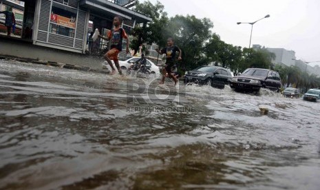 Pengendara nekad menerobos genangan air di Jalan Gunung Sahari, Jakarta, Ahad (12/1).  (Republika/Agung Supriyanto)