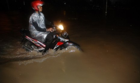 Pengendara roda dua berusaha melintasi banjir di Gedebage, Bandung, Jawa Barat, Jumat (28/10). 