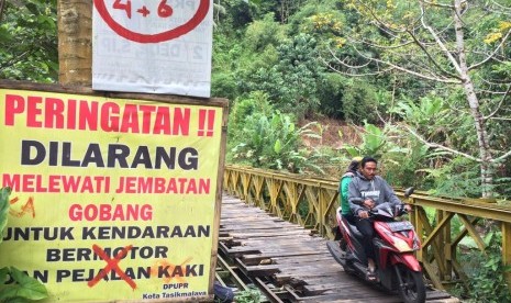 Pengendara roda dua memaksa melintas di Jembatan Gobang yang menghubungkan Kecamatan Purbaratu Kota Tasikmalaya dengan Kecamatan Manonjaya Kabupaten Tasikmalaya, Juma (14/6). 