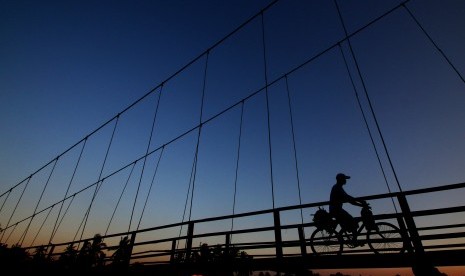 Pengendara sepeda melintasi Jembatan Gantung Muara Gembong, Bekasi, Jawa Barat, Kamis (8/6). Jembatan itu menjadi satu-satunya sarana penyeberangan antardesa yang terkena dampak abrasi di Kecamatan Muara Gembong. 