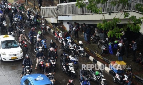 Pengendara sepeda motor berteduh di bawah Jembatan Penyeberangan Orang (JPO) saat hujan turun, Jakarta, Kamis (9/6). Memasuki musim hujan, polisi meminta pengendara untuk tidak berteduh di sembarang tempat, khususnya di bawah Jembatan Penyeberangan Orang (