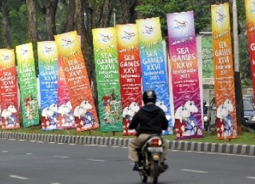 Pengendara sepeda motor melaju di samping deretan banner sosialisasi perhelatan pesta olahraga negara-negara Asean, SEA Games ke-26 Indonesia di Jakarta.