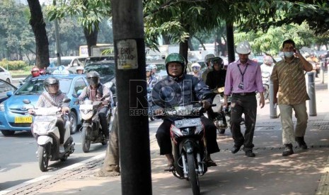   Pengendara sepeda motor melaju di trotoar di Jalan Sudirman, Jakarta Pusat, Jumat (19/7).    (Republika/ Yasin Habibi)